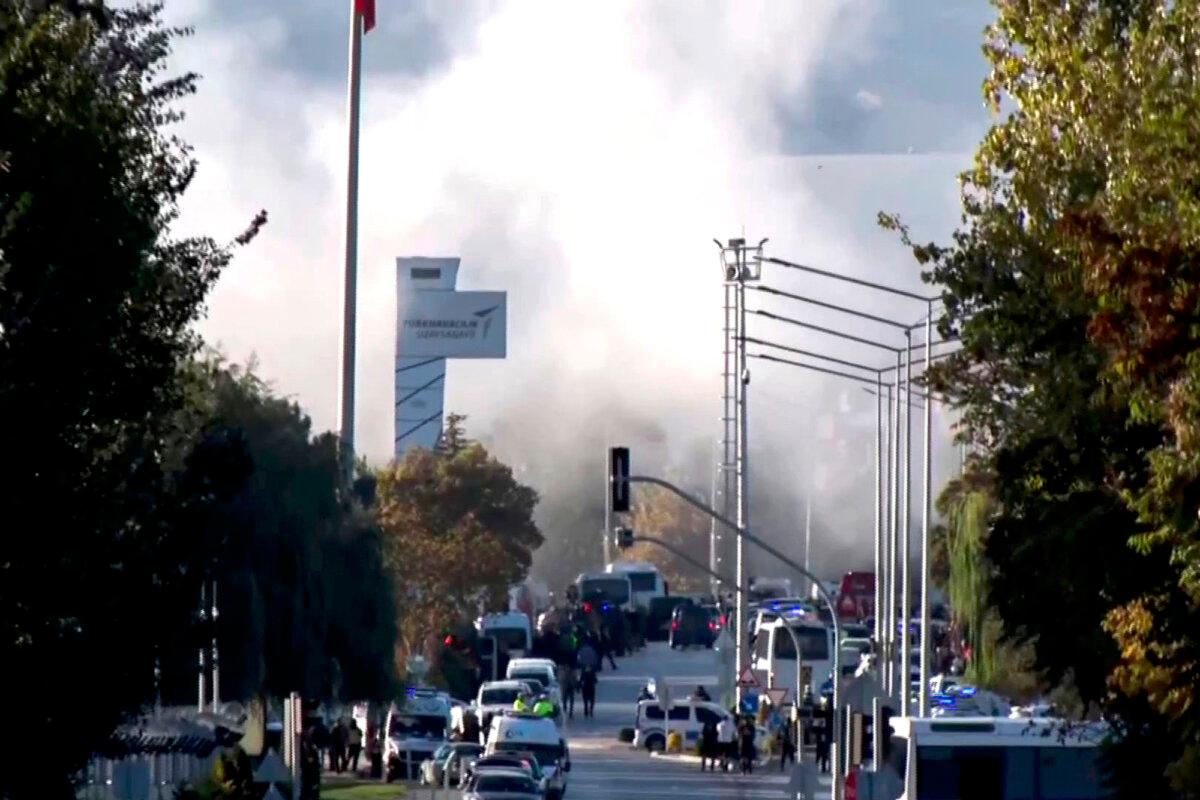 Smoke rises as emergency rescue teams and police officers converge outside Turkish Aerospace Industries Inc. on the outskirts of Ankara, Turkey, on Oct. 23, 2024. (IHA via AP)
