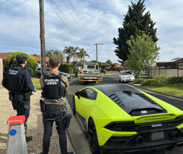 Officers from Operation Viper pictured on Oct. 23, 2024, beside one of the vehicles seized as proceeds of crime after raids on 27 properties across Victoria as part of a crackdown on a syndicate selling illegal tobacco and vapes. (Victoria Police)