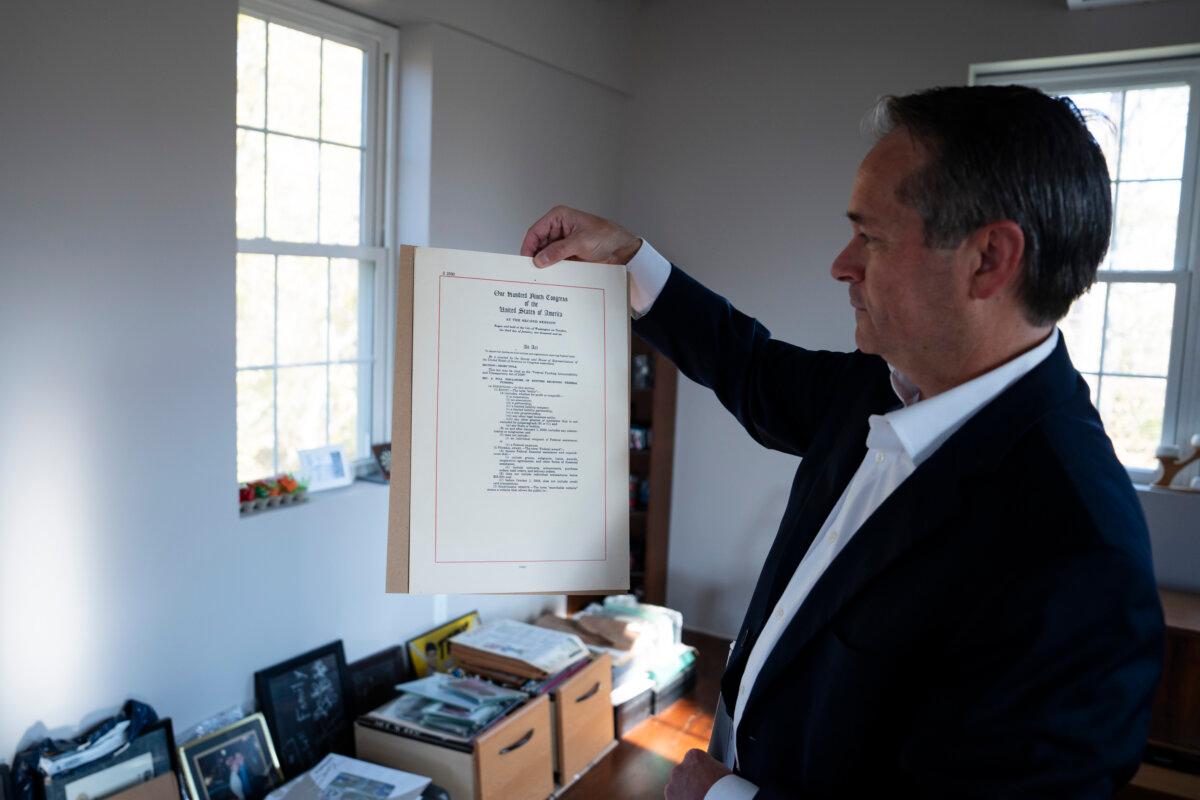 John Hart, Open the Books' new CEO, points to a framed first page of the 2006 Federal Financial Accountability and Transparency Act during an interview with The Epoch Times in his office in Knoxville, Md., on Oct. 29, 2024. (Madalina Vasiliu/The Epoch Times)