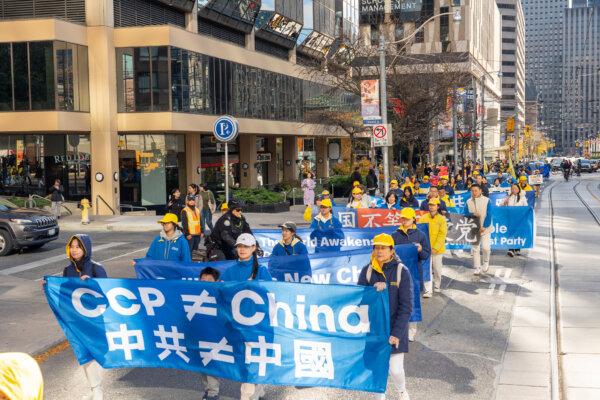 People hold banners as they participate in a parade in downtown Toronto on Nov. 2, 2024, marking the 20th anniversary of the release of "Nine Commentaries on the Communist Party," a book that details the Chinese regime's totalitarian rule and human rights abuses. (The Epoch Times)