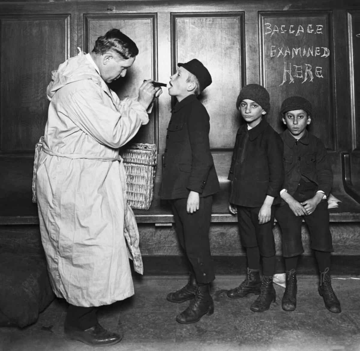 Immigrant children being examined by a city health officer upon arrival at the battery from Ellis Island during the Typhus Scare, c. 1910s. (Public Domain)