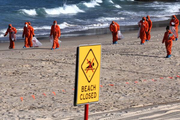 Workers in protective suits conduct a cleanup operation to clear mysterious "tar balls" washed ashore on Coogee Beach in Sydney, Australia, on Oct. 17, 2024. (David Gray/AFP via Getty Images)