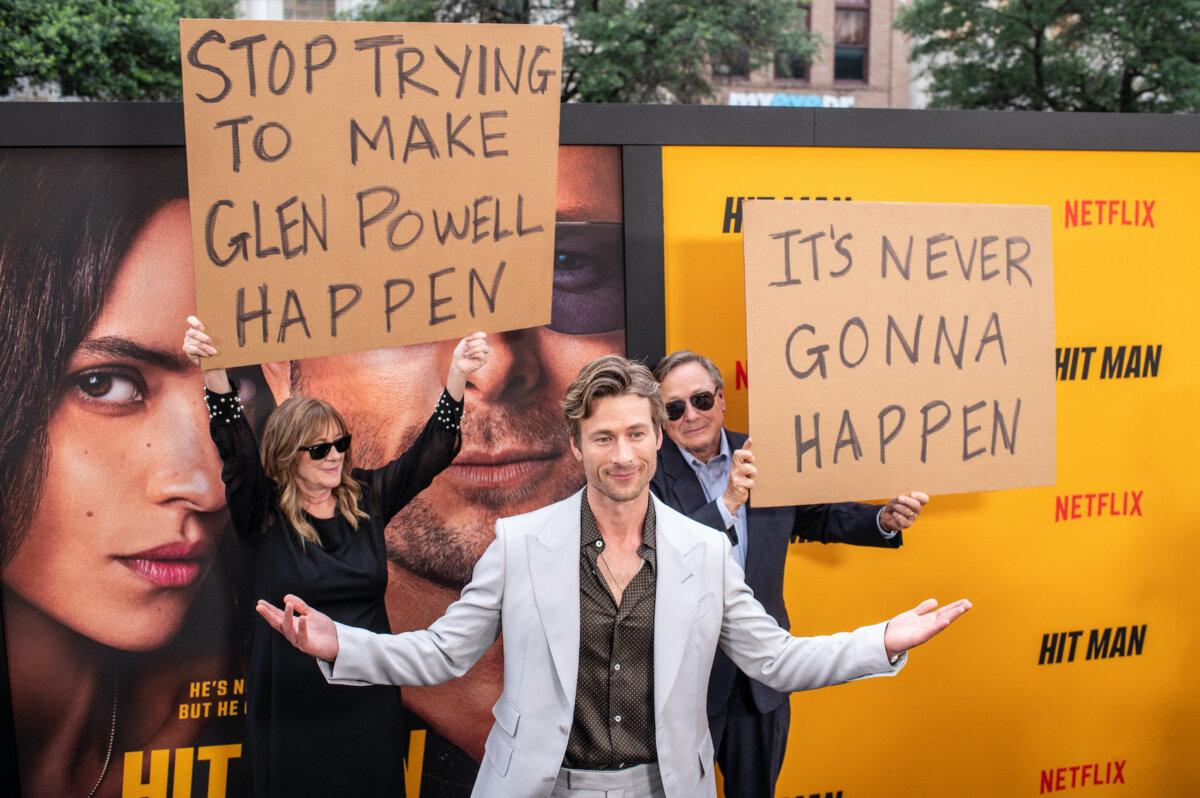 US actor Glen Powell’s parents hold up signs behind him as they attend the special screening of "Hitman" at the Paramount Theatre in Austin, Texas, on May 15, 2024. (Sergio Flores/AFP via Getty Images)