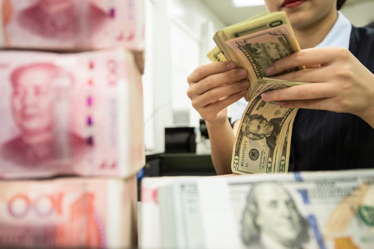A Chinese bank employee counts 100-yuan notes and U.S. dollar bills at a bank counter in Nantong in China's eastern Jiangsu province on Aug. 6, 2019. (STR/AFP via Getty Images)