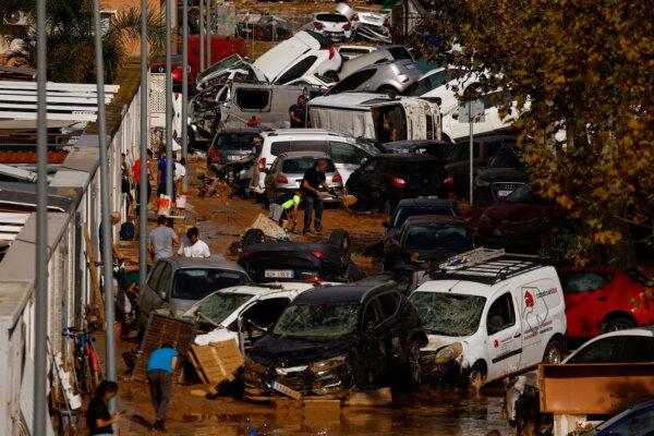 People clean up a mud-covered street next to piled up cars after heavy rains in Alfafar, in Valencia, Spain, on Nov. 1, 2024. (Susana Vera/Reuters)