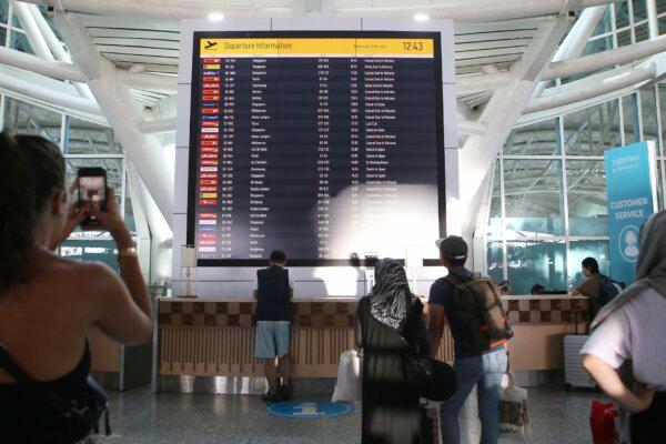 Passengers look at a flight information board showing a number of flights canceled because of the eruption of Mount Lewotobi Laki Laki at Ngurah Rai International Airport in Bali, Indonesia, on Nov. 13, 2024. (Firdia Lisnawati/AP Photo)