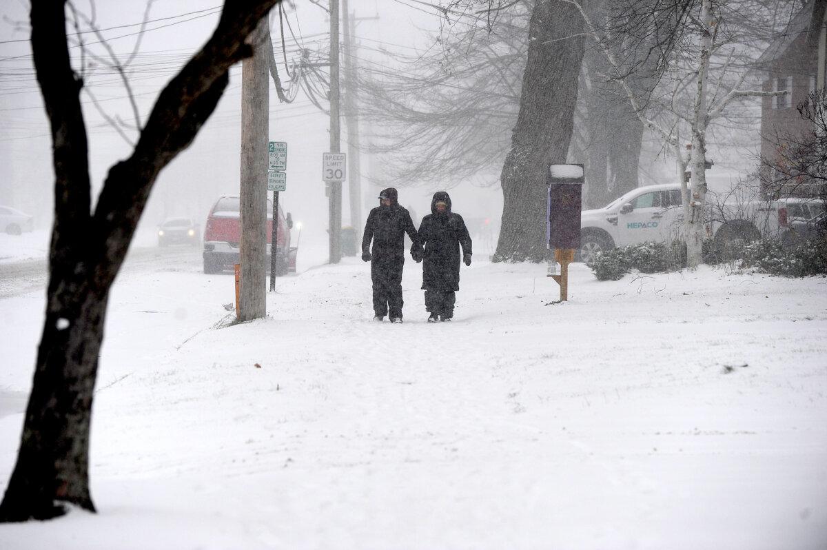 A couple makes their way through lake effect snow to attend the annual Hamburg Holiday Parade in Hamburg, N.Y., on Nov. 30, 2024. (John Normile/Getty Images)