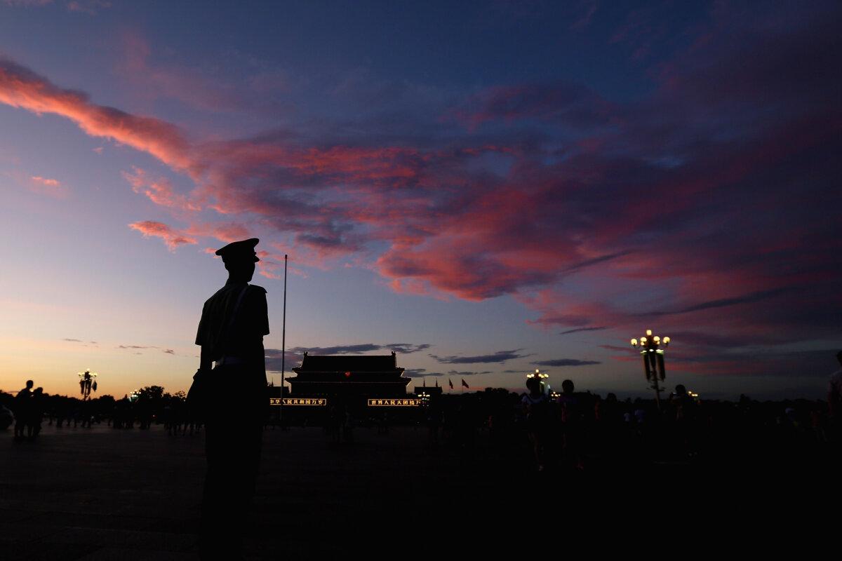 A Chinese paramilitary policeman guards Tiananmen Square under crimson clouds at sunset after several days of heavy air pollution in Beijing on July 4, 2013. (Feng Li/Getty Images)