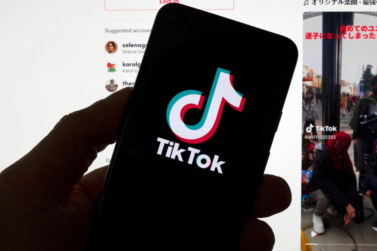 The TikTok logo is displayed on a mobile phone in front of a computer screen which displays a TikTok home page, in Boston, on March 18, 2023. (Michael Dwyer/AP Photo, File)
