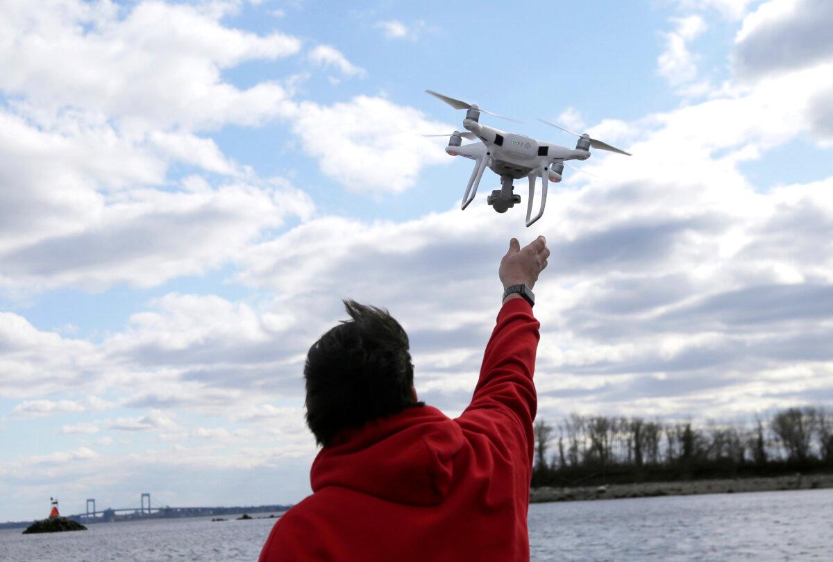 A drone operator helps to retrieve a drone after photographing over Hart Island in New York City on April 29, 2018. (Seth Wenig/AP Photo)