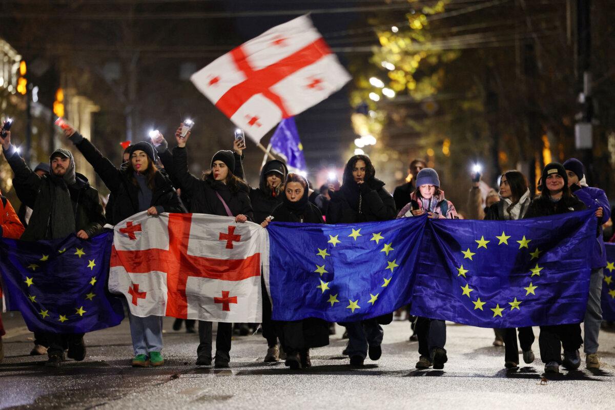 Anti-government protesters hold Georgian and European Union flags during a demonstration in central Tbilisi on Dec. 13, 2024. (Photo by GIORGI ARJEVANIDZE/AFP via Getty Images)