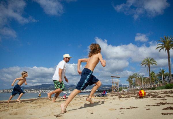 Two boys play football with their father at Can Pere Antoni Beach in Palma de Mallorca, Spain, on April 26, 2020. (Jaime Reina/AFP via Getty Images)