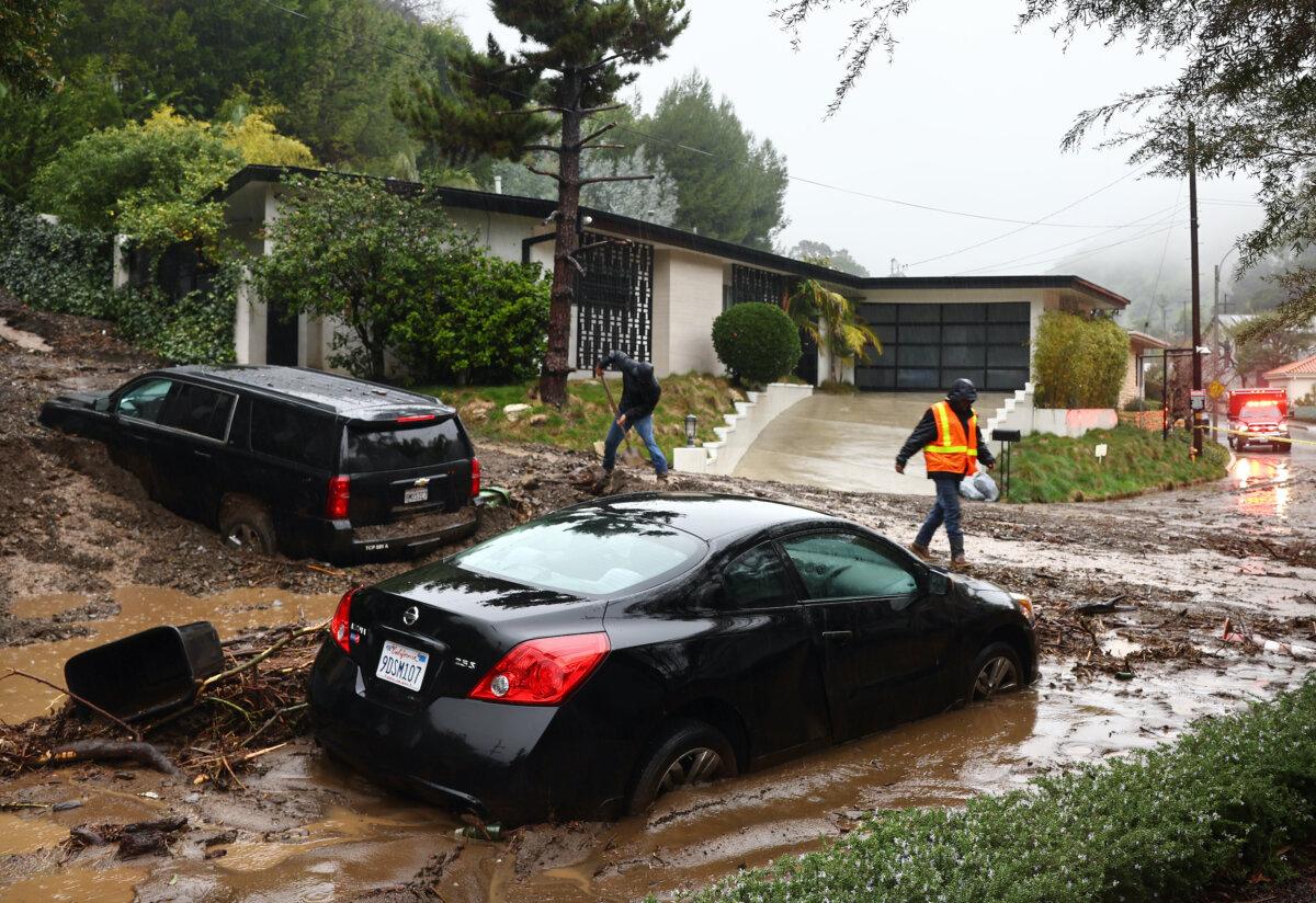 People attempts to clear away debris from a mudslide after a powerful long-duration atmospheric river storm in Beverly Hills, Calif., on Feb. 5, 2024. (Mario Tama/Getty Images)