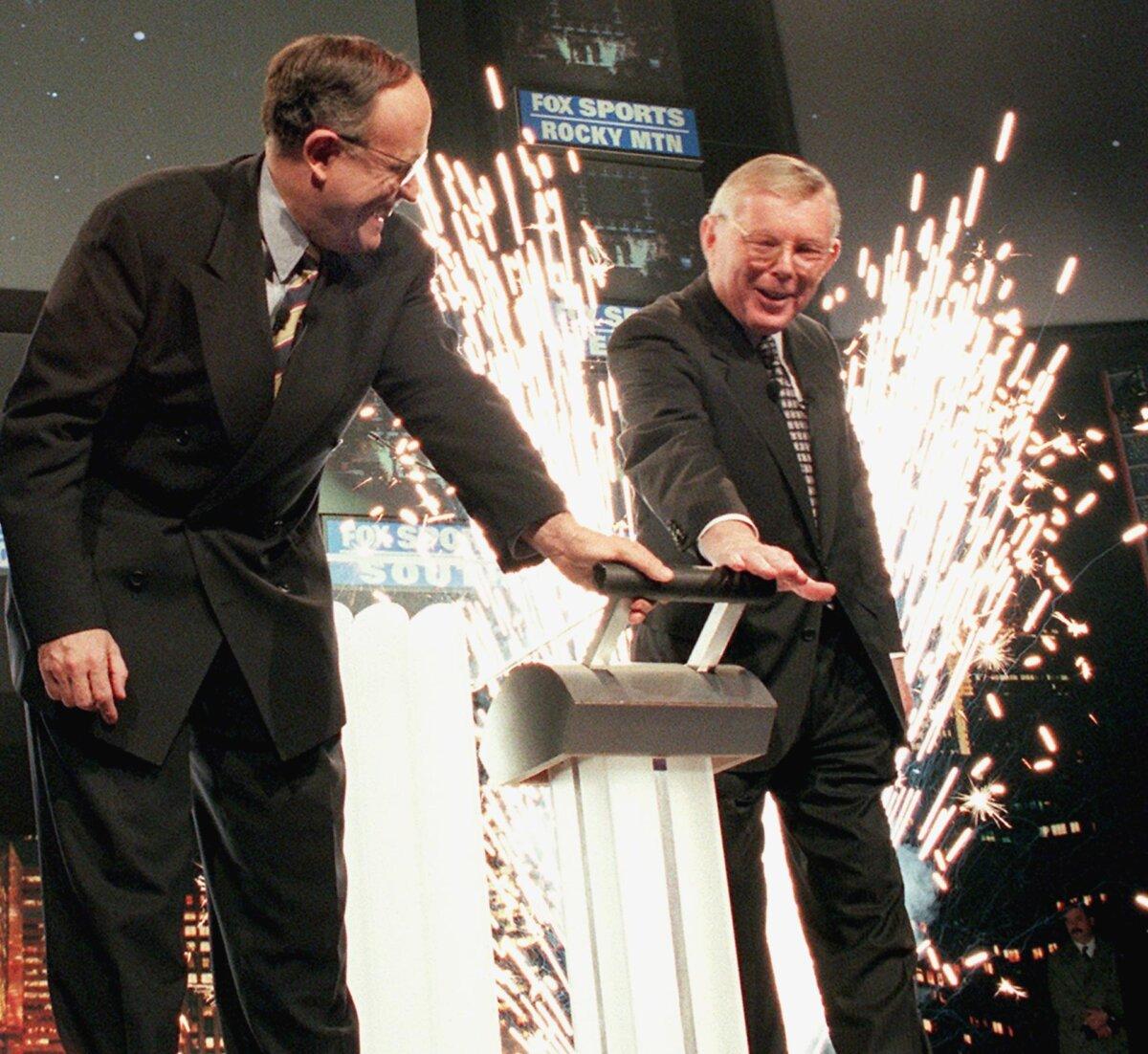 New York City Mayor Rudolph Giuliani (L) and Cablevision Systems chairman Charles Dolan (R) turn a symbolic switch to launch the formation of the Fox Sports Net in New York on Jan. 28, 1998. (Stan Honda/AFP via Getty Images)