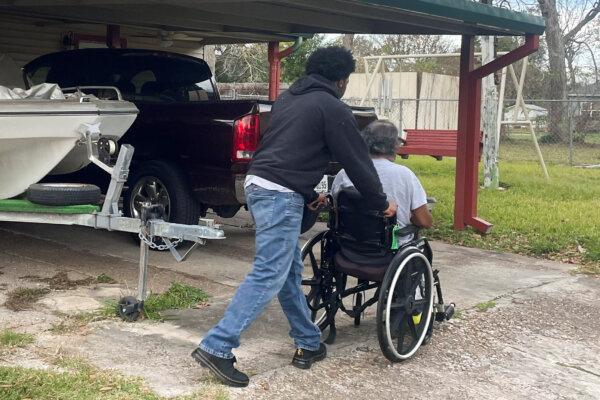 Abdur-Rahim Jabbar, half-brother of Shamsud-Din Jabbar, the Texas man accused of crashing a truck into New Year's Day revelers in New Orleans, wheels his dad in front of their house in Beaumont, Texas, on Jan. 2, 2025. (Arathy Somasekhar/Reuters)