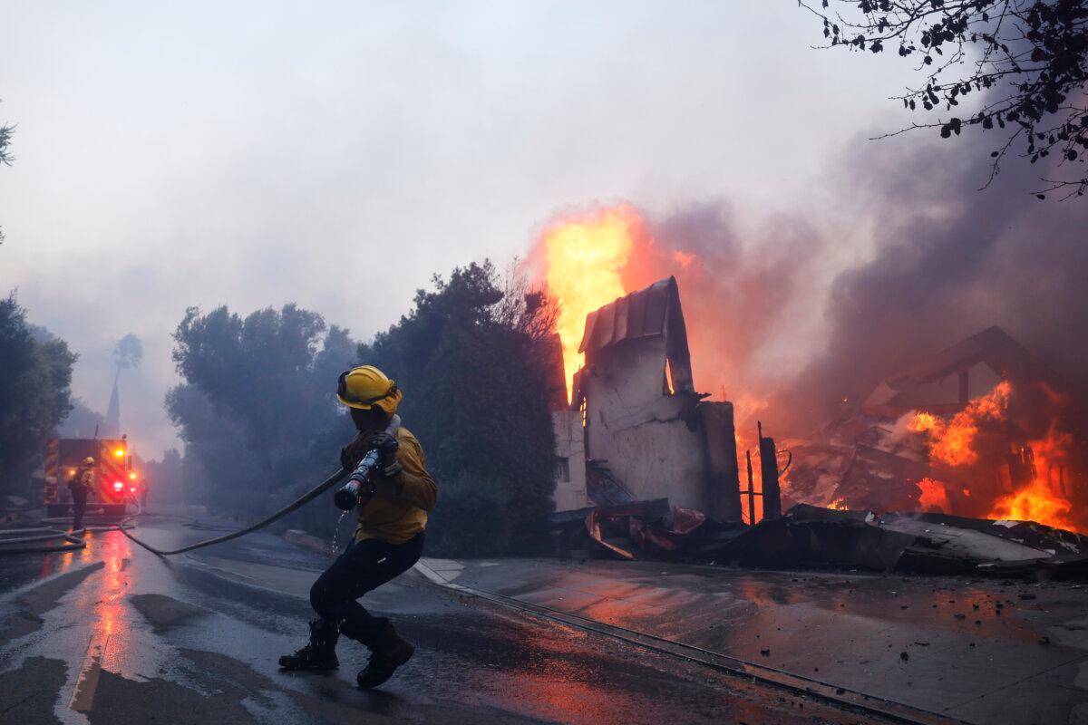A firefighter battles the advancing Palisades Fire as it burns a structure in the Pacific Palisades neighborhood of Los Angeles on Jan. 7, 2025. (Etienne Laurent/AP Photo)