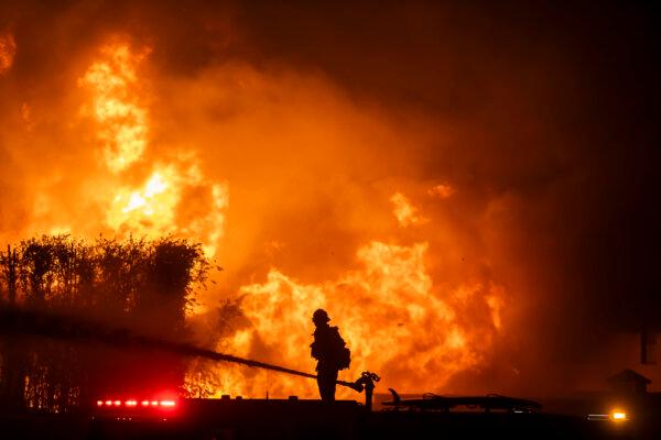 A firefighter stands on top of a fire truck to battle the Palisades Fire while it burns homes on the Pacific Coast Highway amid a powerful windstorm in Los Angeles on Jan. 8, 2025. (Apu Gomes/Getty Images)
