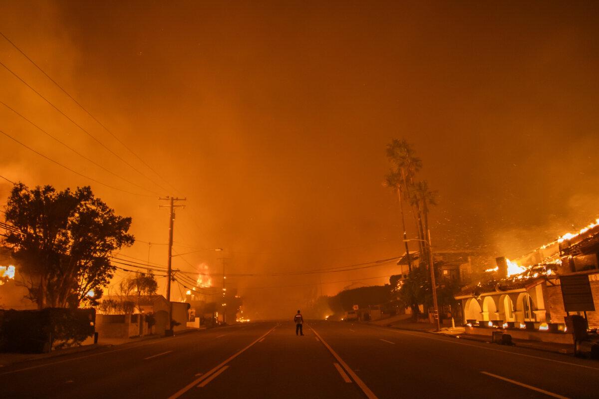 A man watches the flames from the Palisades Fire burning homes on the Pacific Coast Highway amid a powerful windstorm on Jan. 8, 2025, in Los Angeles, Calif. (Apu Gomes/Getty Images)