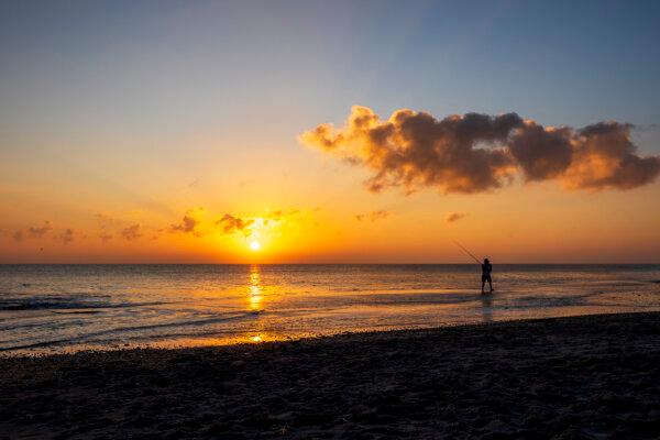 A fisherman is silhouetted as the sun rises over the Atlantic Ocean on New Year’s Day as seen from Hangar’s Beach across from Patrick Space Force Base in Brevard County, Fla., on Jan. 1, 2025. (Patrick Connolly/Orlando Sentinel/TNS)