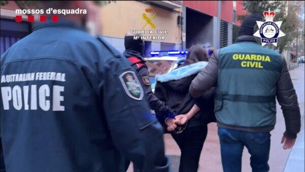 A suspect is led away by Spanish Police as an AFP officer observes the operation. (Australian Federal Police)