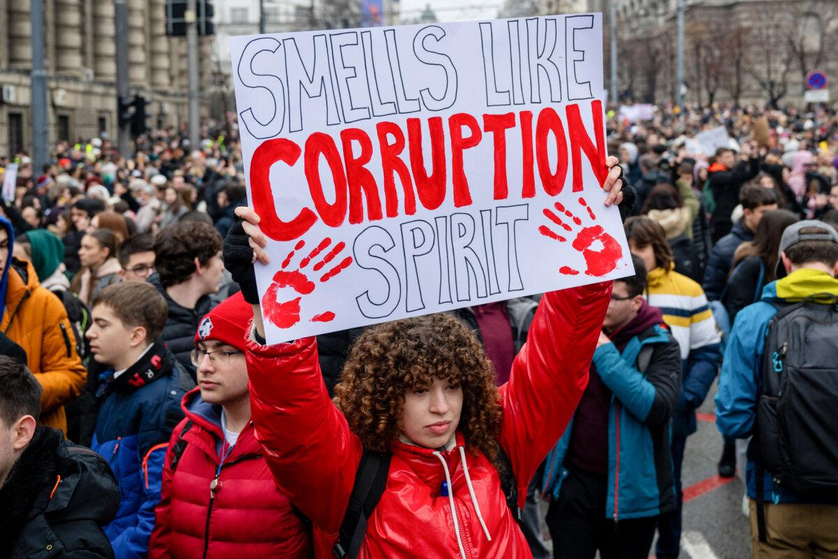 A woman holds a placard reading "Smells like corruption spirit" during a demonstration in front of the government building in central Belgrade on Jan. 24, 2025, (Andrej Isakovic/AFP via Getty Images)