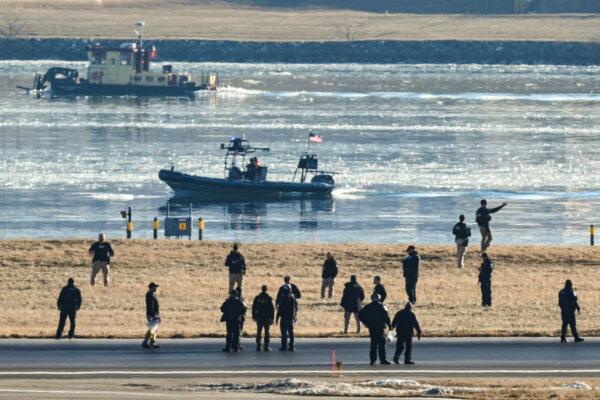 People, including law enforcement members, are seen on a runway at Ronald Reagan Washington National Airport as rescue crews search the waters of the Potomac River after a passenger plane on approach to Reagan crashed into the river after colliding with a US Army helicopter, near Washington on Jan. 30, 2025. (Andrew Caballero-Reynolds/AFP via Getty Images)