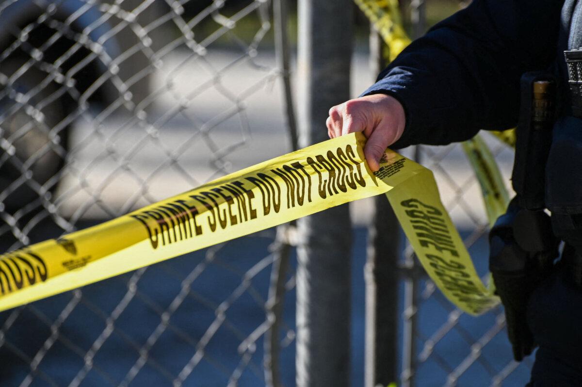 An officer puts up tape at a crime scene. (Samantha Laurey/AFP via Getty Images)