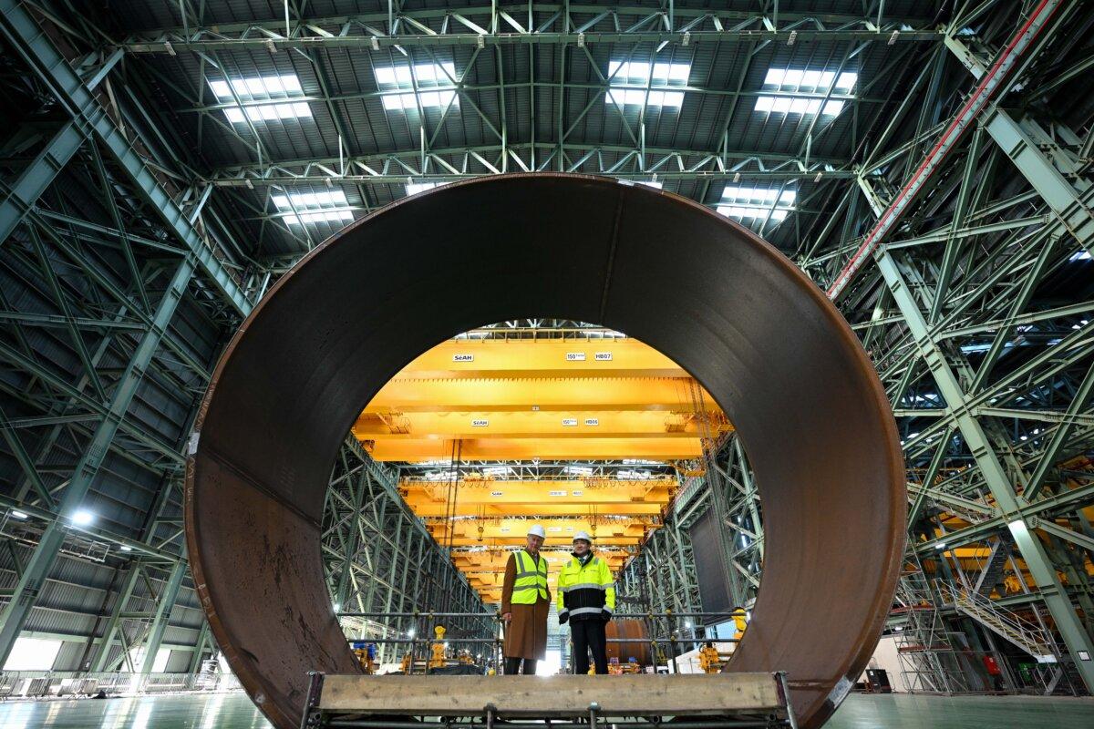 King Charles III (L) and SeAHn steel President Joosung Lee stand in the section of a Monopile foundation during a visit to at SeAH factory, in Middlesbrough, England, on Feb. 13, 2025. (Oli Scarff - WPA Pool/Getty Images)
