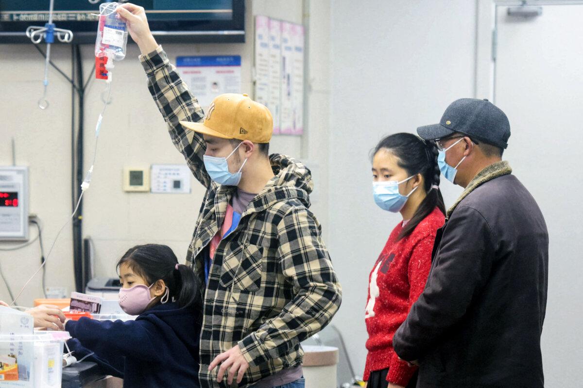A family member (2nd L) holds an IV drip for a child (L) receiving care at the pediatric department of a hospital in Hangzhou, eastern China's Zhejiang province, on Jan. 6, 2025. (AFP/China)