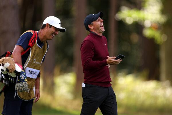 Rory McIlroy of Northern Ireland laughs at his mobile phone alongside his caddie, Harry Diamond during the Pro-Am prior to the BMW PGA Championship at Wentworth Golf Club in Virginia Water, England, on Sept. 13, 2023. (Richard Heathcote/Getty Images)