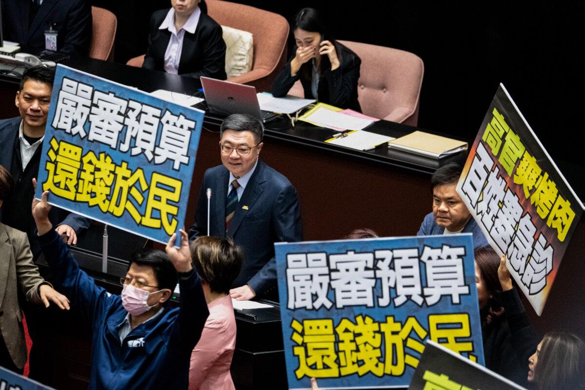Lawmakers from the opposition Kuomintang (KMT) attempt to disrupt proceedings by blocking Premier Cho Jung-tai, from the ruling Democratic Progressive Party (DPP), with placards during a session at the Parliament in Taipei on Feb. 25, 2025. (Yu Chien Huang/AFP via Getty Images)