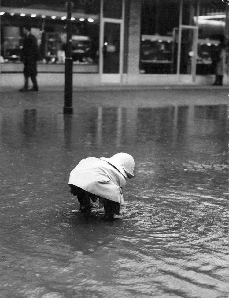 A child standing and looking for something in water. Unknown photographer. (Public Domain)