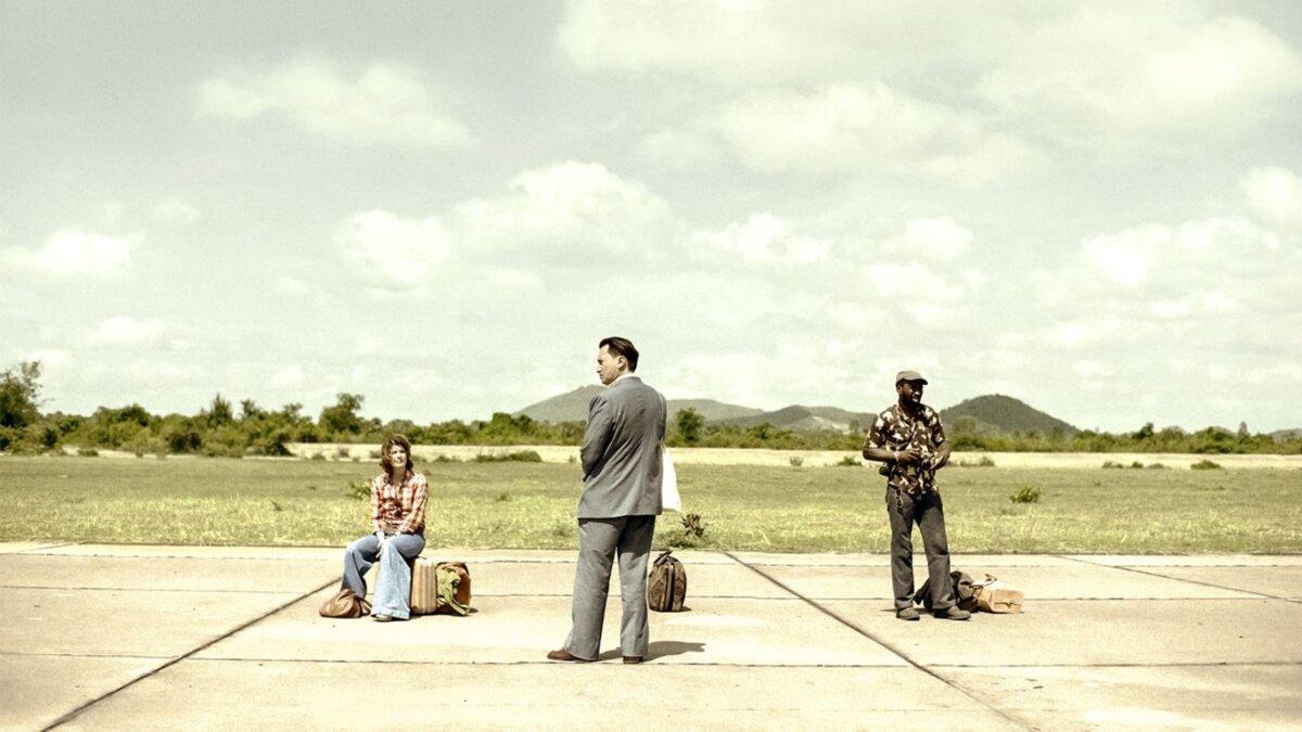 (L–R) Lise Delbo (Irène Jacob), Alain Cariou (Grégoire Colin), and Paul Thomas (Cyril Gueï) on the runway, in “Meeting With Pol Pot.” (Strand Releasing)