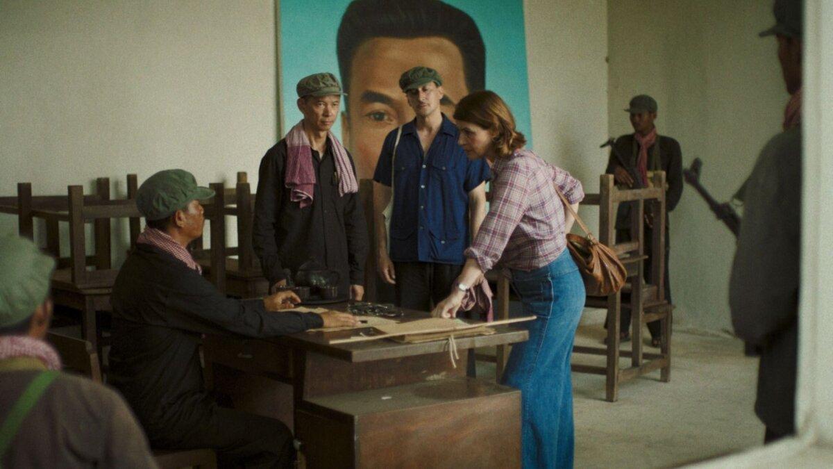 (L–R) Camarade Sung (Bunhok Lim), Alain Cariou (Grégoire Colin), and Lise Delbo (Irène Jacob) with extras, in “Meeting With Pol Pot.” (Strand Releasing)