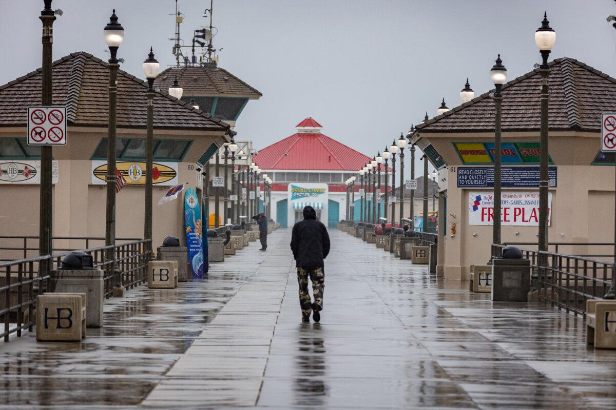 A man walks in the rain in Huntington Beach, Calif., on Feb. 20, 2024. (John Fredricks/The Epoch Times)
