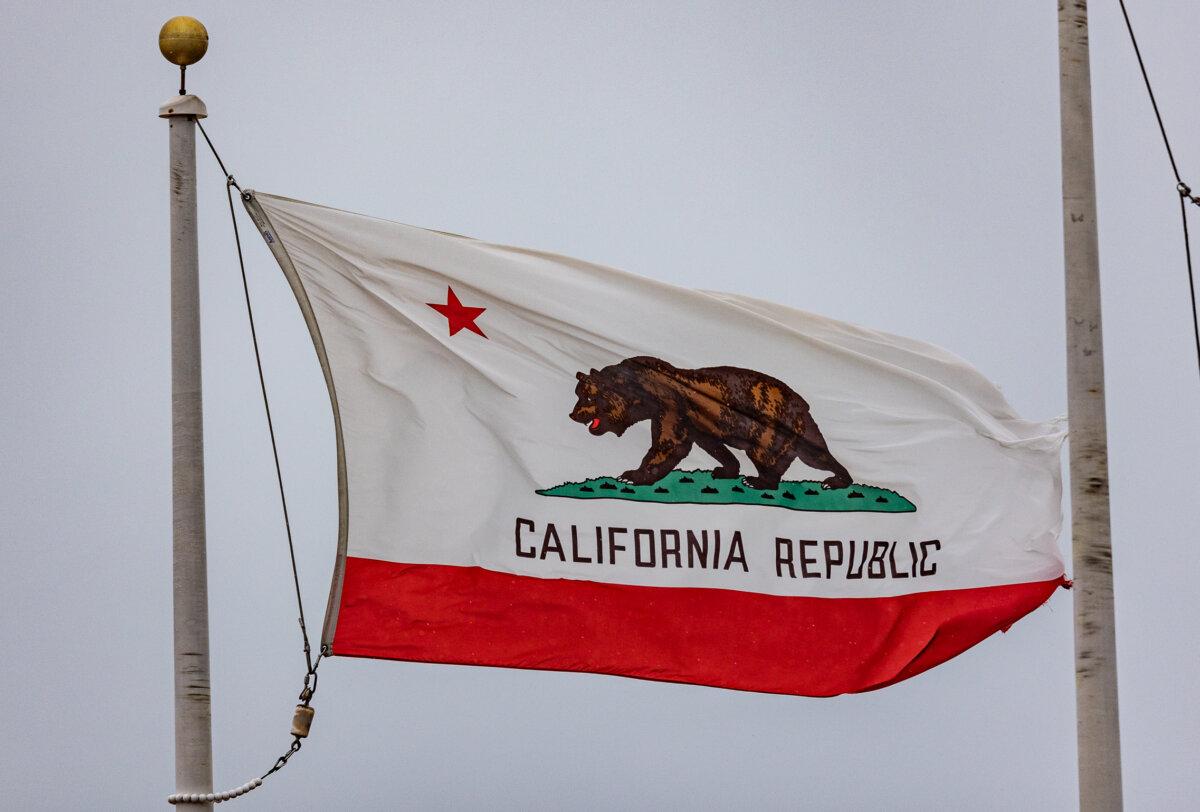 A California state flag billows during a storm in Huntington Beach, Calif., on Feb. 20, 2024. (John Fredricks/The Epoch Times)