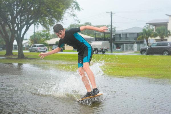 A boy uses his 'boogie board' on a flooded patch of grass near a shore line in Scarborough Brisbane, Australia, on March 09, 2025. (Asanka Ratnayake/Getty Images)