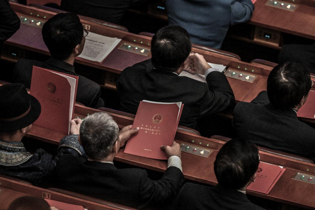 Chinese delegates hold meeting documents during the closing session of the 14th National People's Congress (NPC) at the Great Hall of the People in Beijing on March 11, 2024. (Jade Gao/AFP via Getty Images)