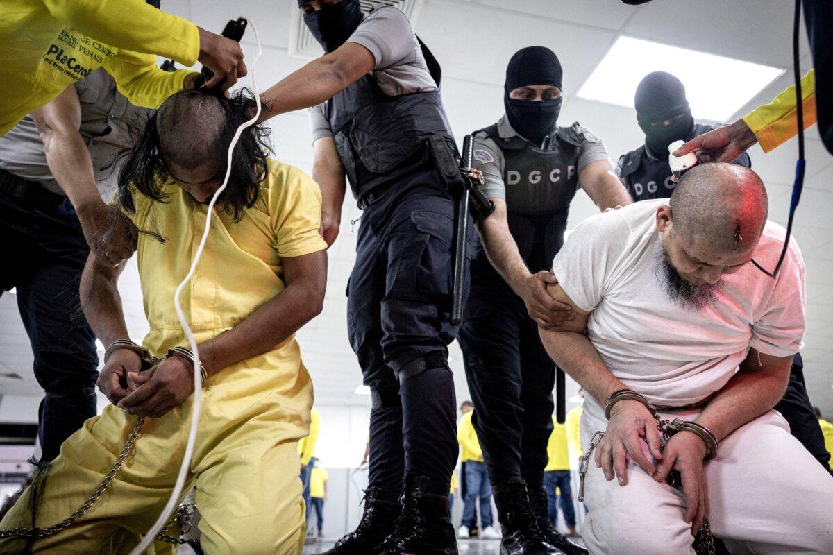 Salvadoran police officers cut the hair of alleged members of the Tren de Aragua recently deported by the U.S. government to be imprisoned in the Terrorism Confinement Center (CECOT) prison, as part of an agreement with the Salvadoran government, in Tecoluca, El Salvador, in this handout image obtained March 16, 2025. (Secretaria de Prensa de la Presidencia/Handout via Reuters)