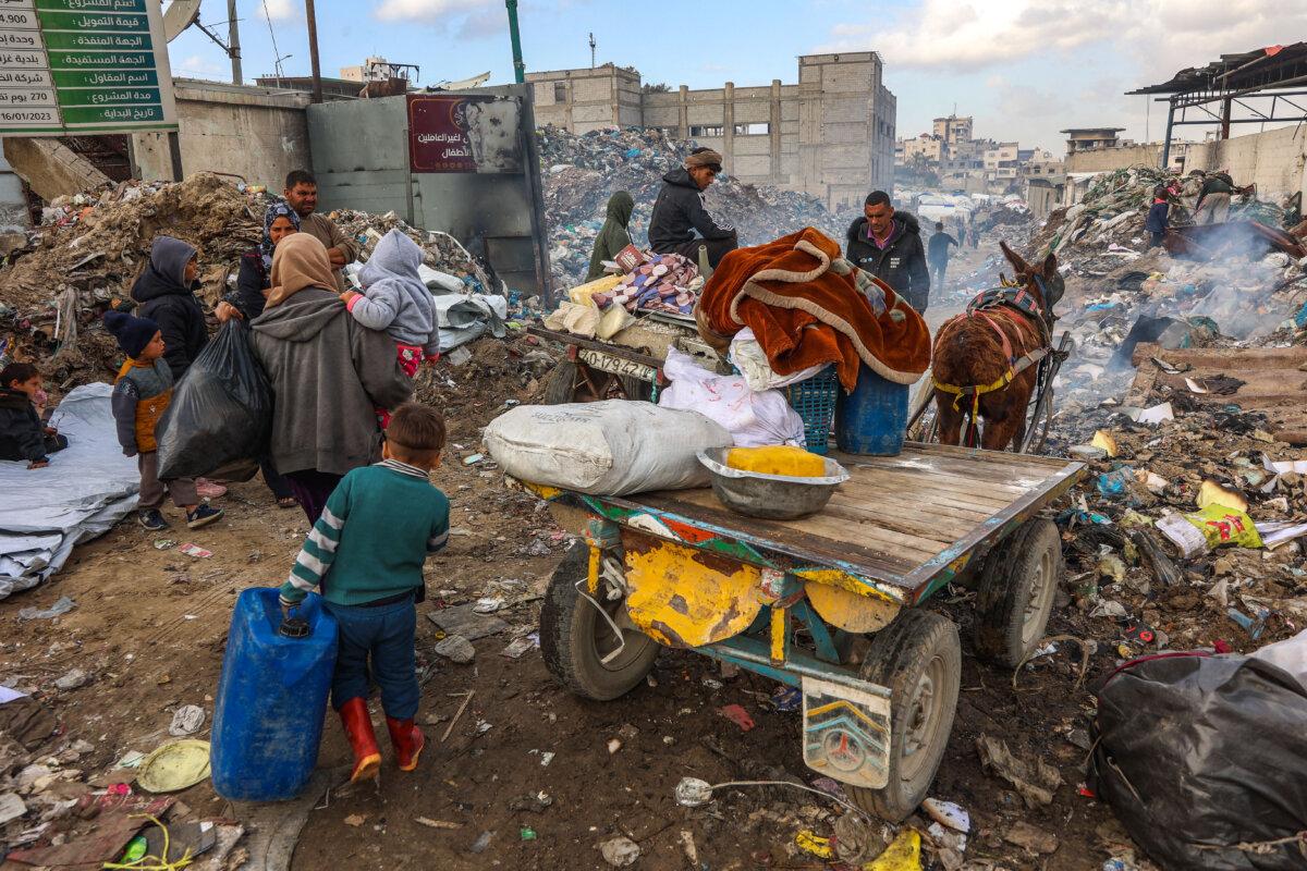 Displaced Palestinians carry their belongings as they set up camp at a landfill in the Yarmuk area in Gaza City on March 20, 2025. (Omar al-Qattaa/AFP via Getty Images)