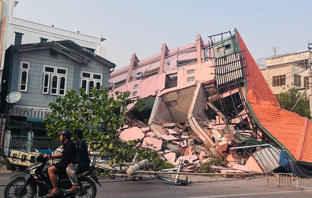 People will drive on bikes past the collapsed buildings of Mandalay after the earthquake in central Burma on March 28, 2025 (STR/AFP via Getty Images)