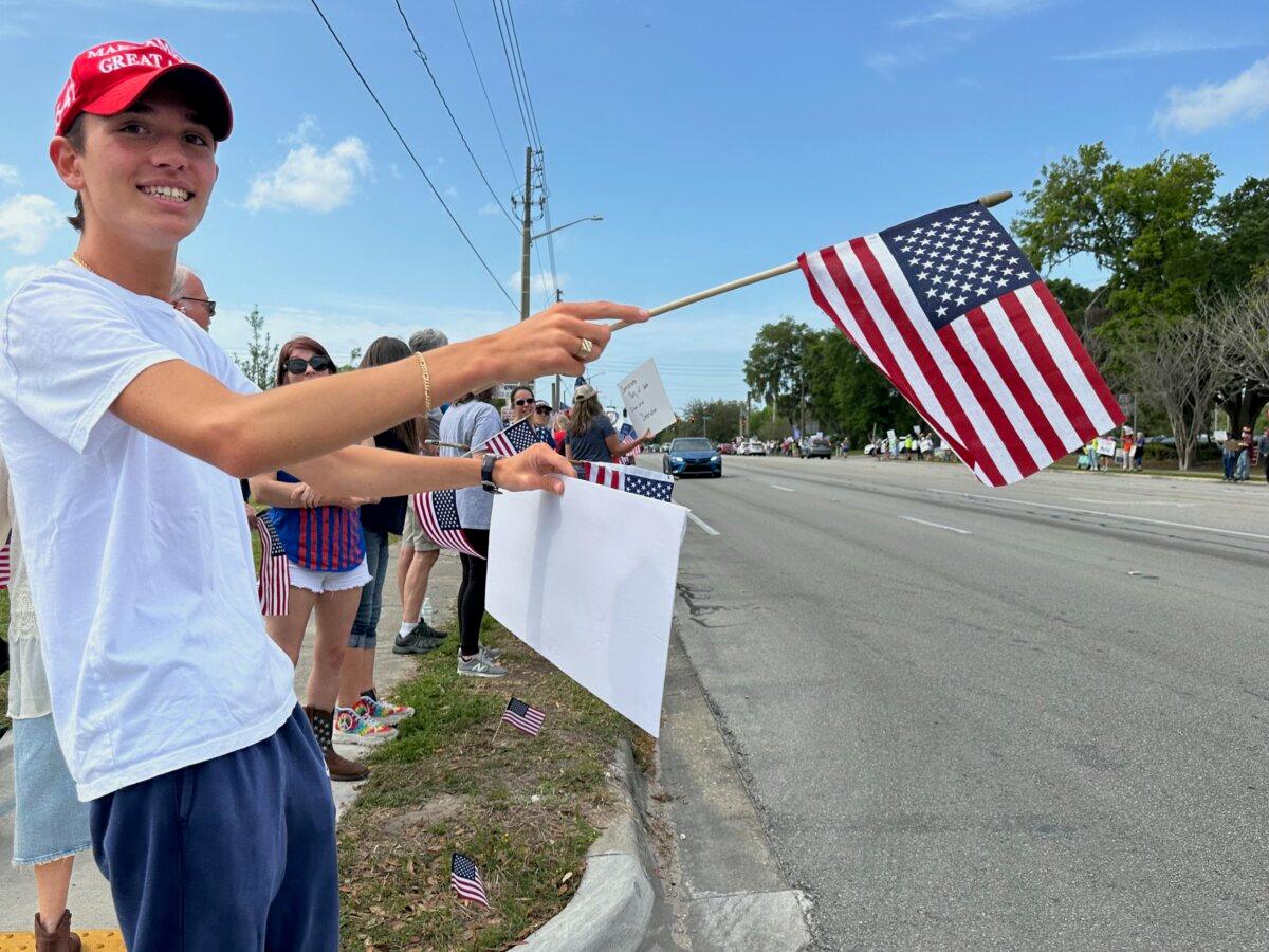 College student Tyler Scaglione holds a sign calling Democrats "hypocrites" during a rally to support Elon Musk, Tesla, and President Donald Trump at a Tesla dealership in Gainesville, Fla., on March 29, 2025. (Nanette Holt/The Epoch Times)