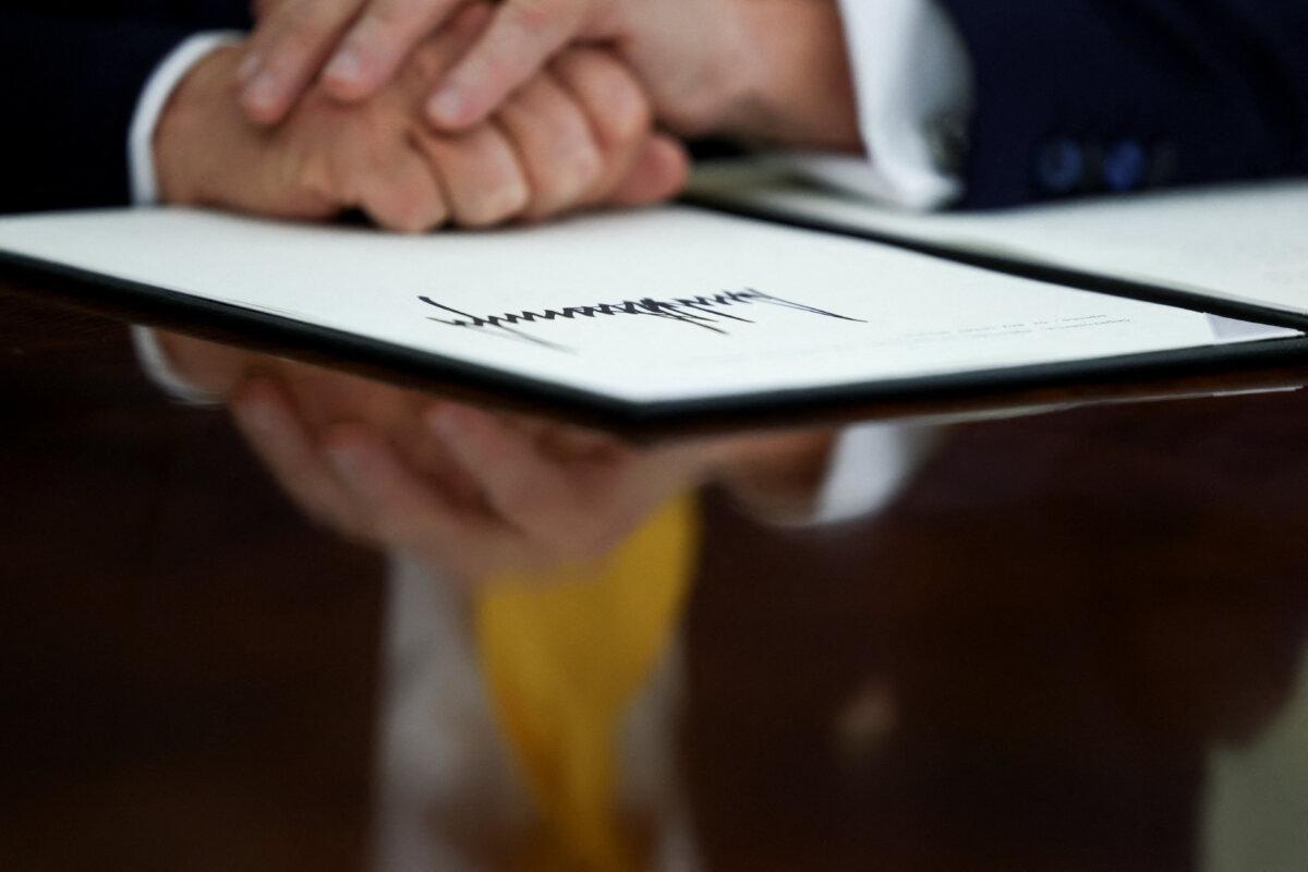 President Donald Trump places his hands on a signed executive order in the Oval Office on March 7, 2025. (Evelyn Hockstein/Reuters)