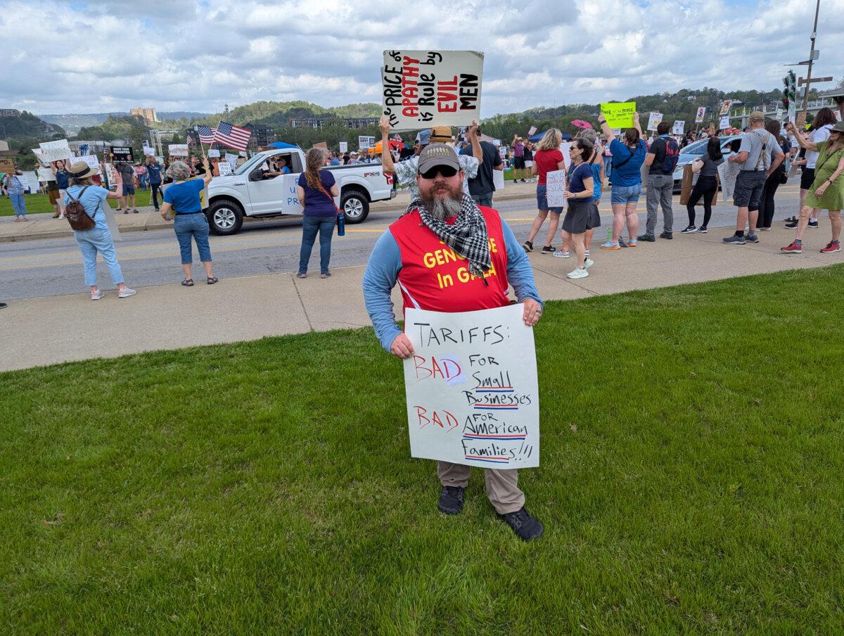 Devin McCullough holds up a poster as he takes part in a protest against President Donald Trump and Elon Musk, in Chattanooga, Tenn., on April 5, 2025. (Ryan Morgan/The Epoch Times)