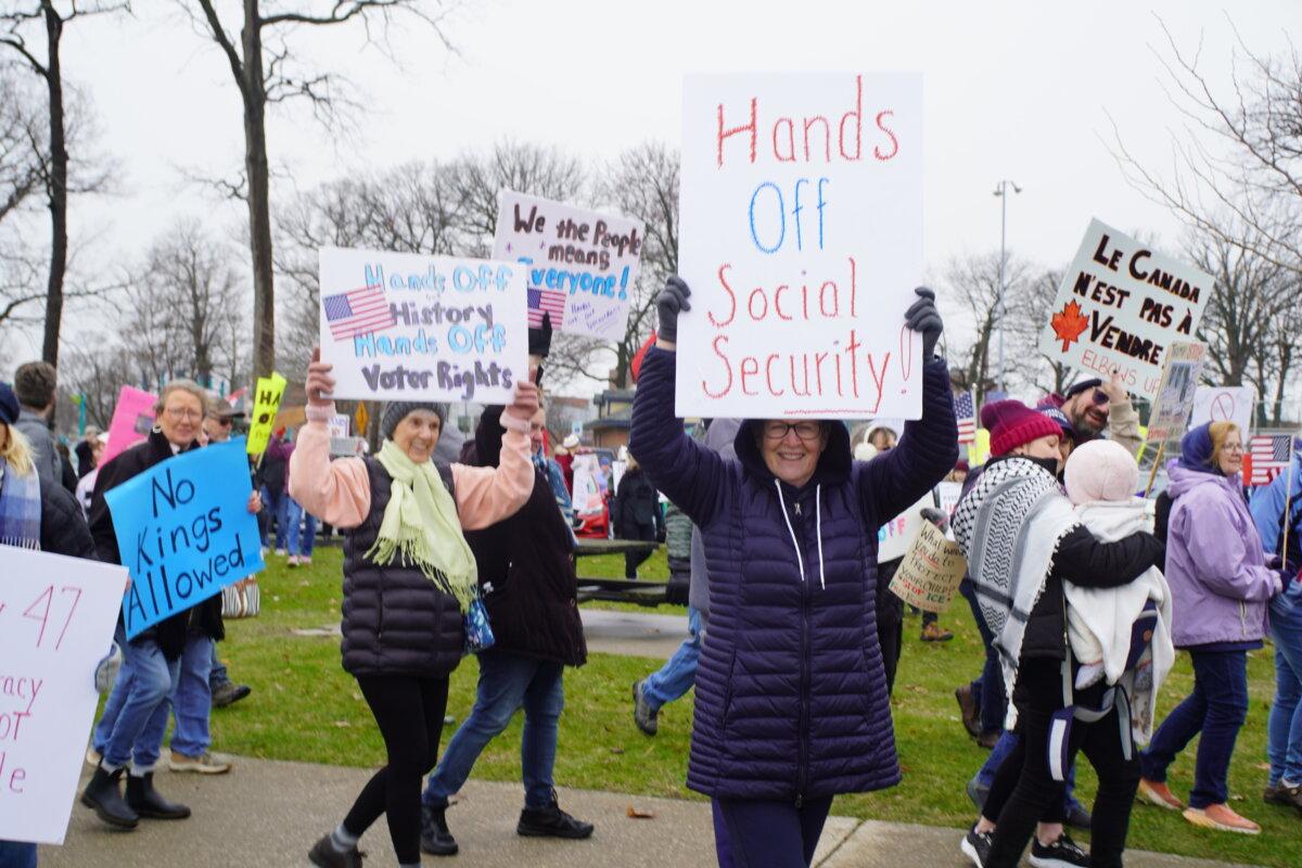 Damp, cold weather did not deter these protesters from bringing their homemade signs to a "Mobilization Day" rally in Port Huron, Mich., on April 5, 2025. (Steven Kovac/Epoch Times)