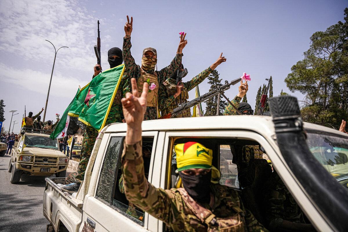 Kurdish-led Syrian Democratic Force fighters wave flags and flash victory signs from a vehicle during a convoy procession as they leave Aleppo, Syria, on April 9, 2025. (MOHAMAD DABOUL/Middle East Images/AFP via Getty Images)