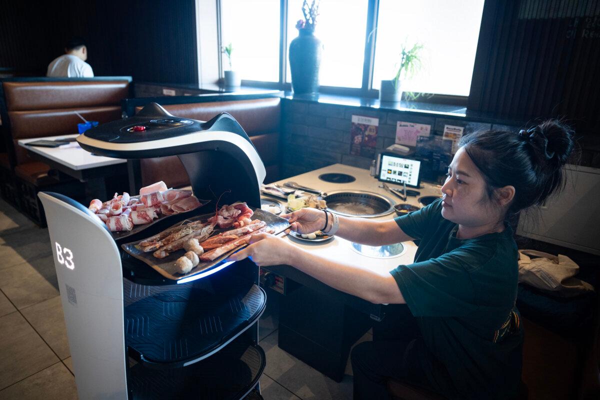 Yok Muangmode retrieves food from a robot server at Shinhwa Korean Steakhouse in Roseville, Minnesota, on Tuesday, March 11, 2025. (Leila Navidi/The Minnesota Star Tribune/TNS)