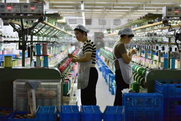Workers check machines at a factory that produces silk cloth in Fuyang, in eastern Anhui Province, China, on April 16, 2025. (STR/AFP via Getty Images)
