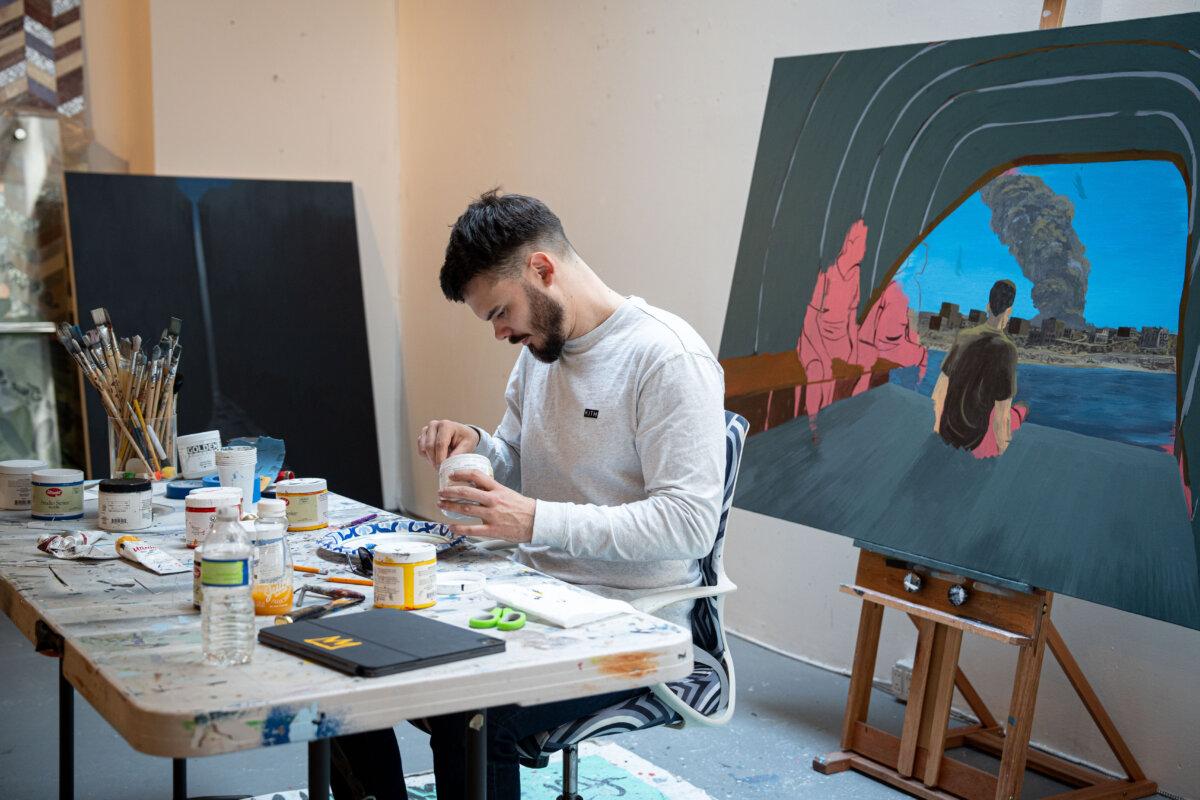 Andrei Kozlov mixes paint next to a painting depicting his captivity at a studio in New York City on April 24, 2025. (Samira Bouaou/The Epoch Times)