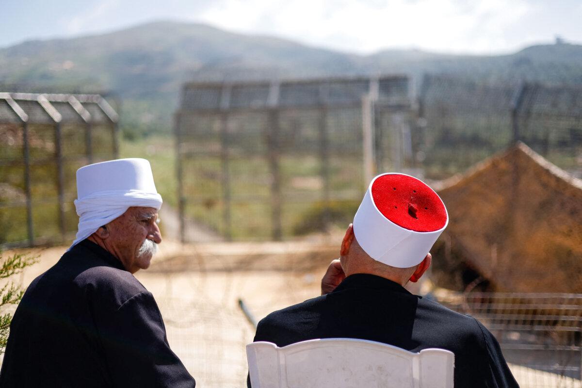 Druze clerics await the arrival of visiting Druze dignitaries from Syria through a barrier guarded by Israeli soldiers near the village of Majdal Shams in the Israeli-annexed Golan Heights on April 25, 2025. (Jalaa Marey/AFP via Getty Images)